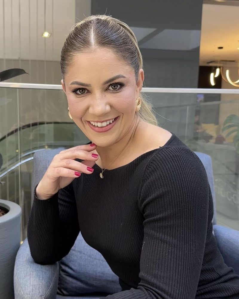 Erica Hartmann sorrindo, de vestido preto